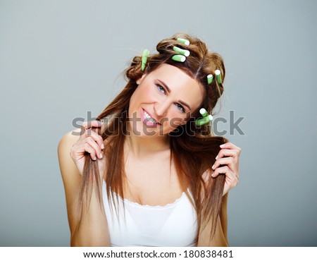 beautiful and cheerful girl with brown hair,  dressing her  hair with green rollers