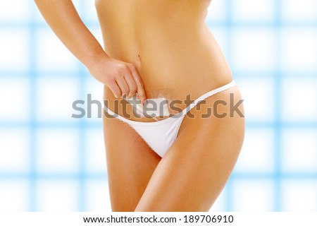 Young woman waxing her belly, hair removal, groin