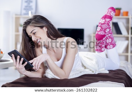 Beautiful woman in bed having coffee, tablet, laptop, computer, phone laughing