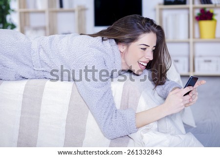 Beautiful woman in bed having tablet, computer and laughing, Woman in bed texting messages with  tablet and laughing in living room