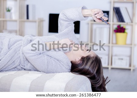 Beautiful woman in bed having tablet, computer and laughing, Woman in bed text messages with  tablet and laughing in living room