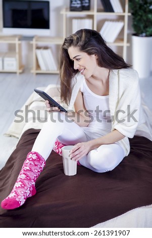 Beautiful woman in bed having tablet computer and laughing, Woman in bed text messages with  tablet and laughing in living room