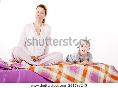 Cute little girl with her mother lying on a bed, Attentive mother hugging her daughter lying on a bed