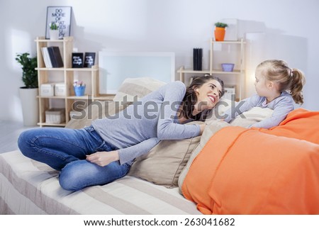 Young mother relaxing with daughter in the living room, shallow depth of field