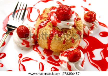 Strawberries pancakes topped with red syrup,served on white plate