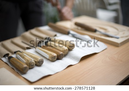 Wood carving tools,artist carves a wood plate in the background
