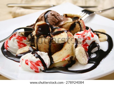 Pancake served on white plate,decorated with red syrup and chocolate ice cream