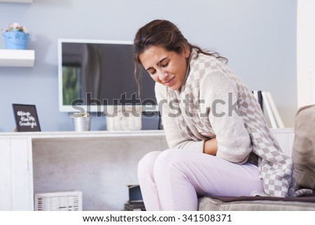 Woman frowning having stomachache sitting on the couch