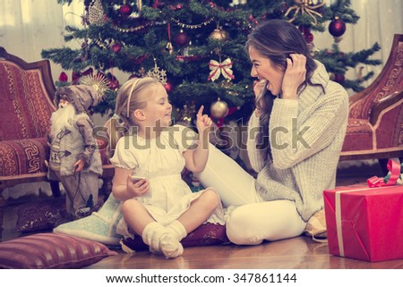 Mother and daughter in front of Christmas tree, opening presents