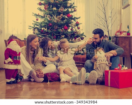 Family in front of Christmas tree, opening presents