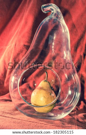 Pear in a Pear Shape Glass Vase on red background