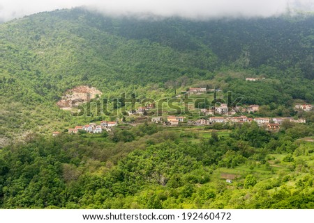 A town surrounded with forest under a mountain slope under the clouds, Istra, Croatia