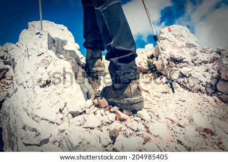 Close up of hiking shoes and trekking poles ascending a mountain