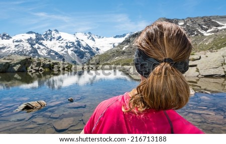 Young woman at a lake watching snow covered mountains