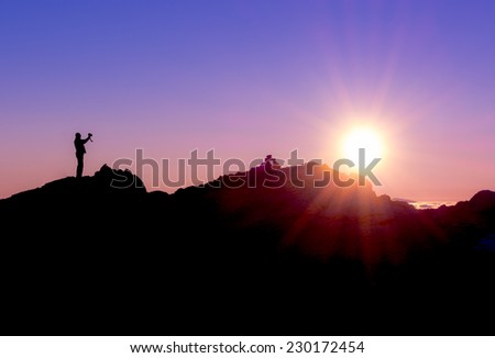 silhouette of a photographer shooting sun rising above the mountains
