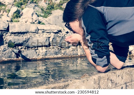 Young girl drinking alpine clean water from a concrete sink