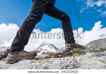 Close-up of hiking shoes on ridge with mountain view in the background.