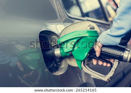 Pumping gas at gas station. Close up of a hand holding fuel nozzle.