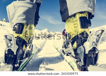 Close up of skier\'s boots and skies from unusual angle. Mountain peak in the background.