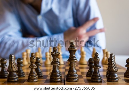 Game of chess. Man forming peace sign with his fingers.