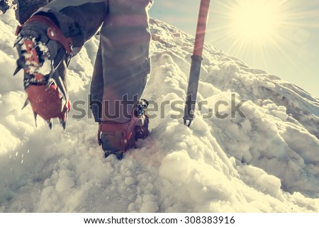 Close up of hiking shoes with crampons. Alpinist ascending a snowy mountain.