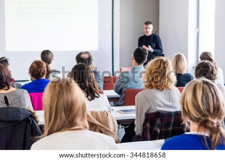 Person delivering a speach. Audience at a conference presentation.