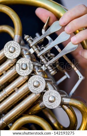 Caucasian male horn player holding rotors on his old golden french horn