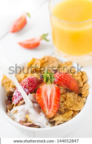 Healthy breakfast with whole grain cereal with milk, fresh strawberry and orange juice