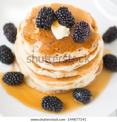 Stack of old-fashioned american pancakes with blackberry and maple syrup