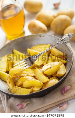 Honey roasted potatoes with skin with rosemary and garlic in an iron pan