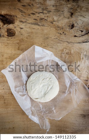 Uncooked pizza dough ball on rustic wooden background