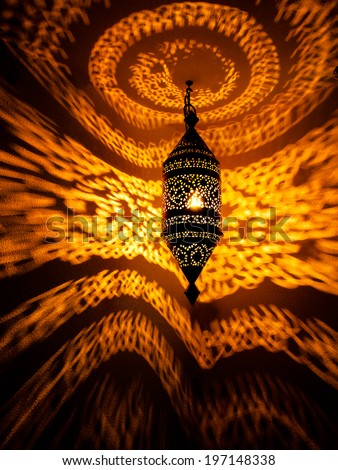 Golden swirling pattern of light on wall from reflected light of Moroccan lamp /Moroccan lamp with golden swirling light pattern reflecting on wall