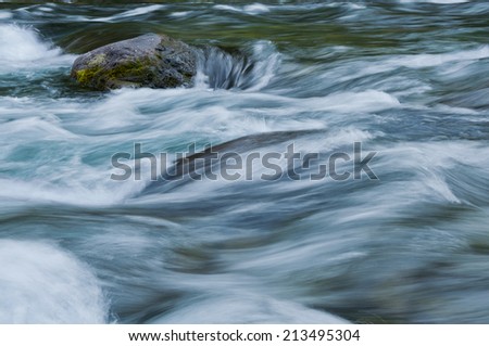 Beautiful horizontal image of sea green flowing water on McKenzie river in Central Oregon. Soft textured background/Closeup of flowing water with sea green and blue colors