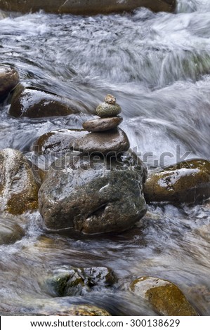 Closeup of stacked rocks on the side of a flowing river/Closeup of stacked rocks in flowing water