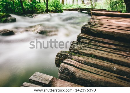Deep forest stream with wooden walk path. Crystal clear water. Plitvice lakes, Croatia