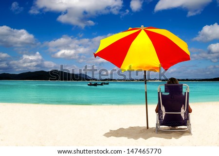 Beautiful woman enjoying the sun under an sun umbrella in front of the sea.