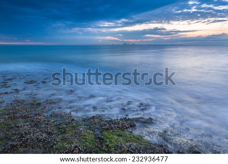 Beach shore at sunrise with view on a distant city