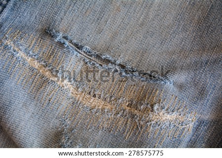 Closeup of tear in old worn out jeans