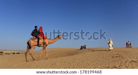 Jaisalmer, India - February 25, 2013: Caravan of camels at the Sam Sand Dune. Camel riding activity for tourists is another income source for desert villagers apart from farming and animal raising