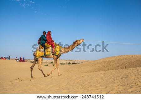 Jaisalmer, India - February 25, 2013: Caravan of camels at the Sam Sand Dune. Camel riding activity for tourists is another income source for desert villagers apart from farming and animal raising