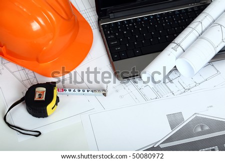 Orange helmet on the house blueprints.