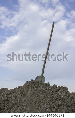 finally done, good job. Shovel in the heap of ground against blue sky