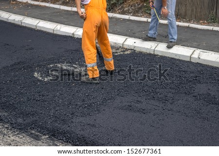 Engineer giving orders to asphalt worker during road construction
