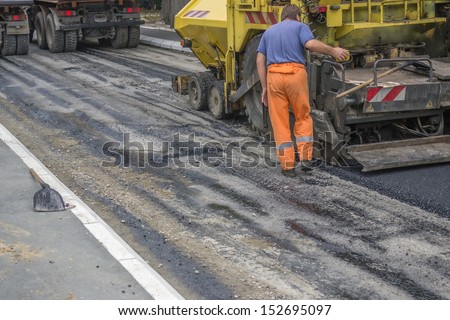 Asphalt paver machine during road construction, road construction crew apply the first layer of asphalt.
