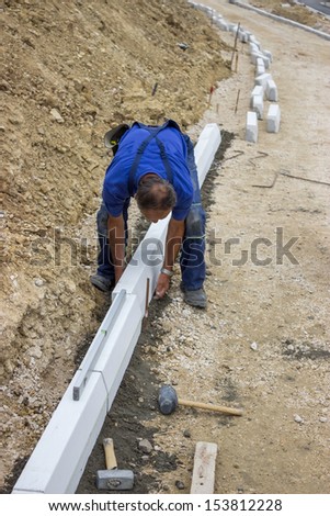 manual worker works with a level, worker leveling concrete curbs of new sidewalk