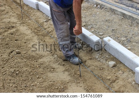 builder worker checking distance with tape measure at construction site. worker measure space for concrete curbs of new sidewalk