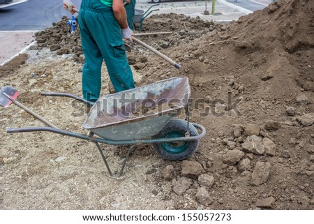 Pile of dirt, using several wheel barrows, workers shoveled and dumped, shoveled and dumped, transporting wheel-barrow-fulls at a residential construction site doing preparation for lawns
