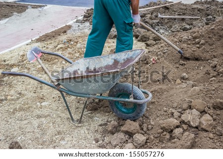 Pile of dirt, using wheel barrow, worker shoveled and dumped, shoveled and dumped, transporting wheel-barrow-fulls at a residential construction site doing preparation for lawns