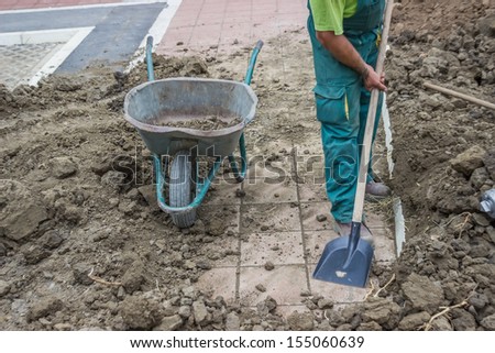 A Worker Shovels Dirt Into A Wheelbarrow, at a residential construction site doing preparation for lawns