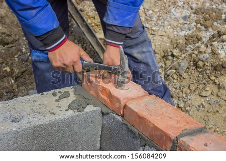 Man laying concrete block and bricks wall at construction site